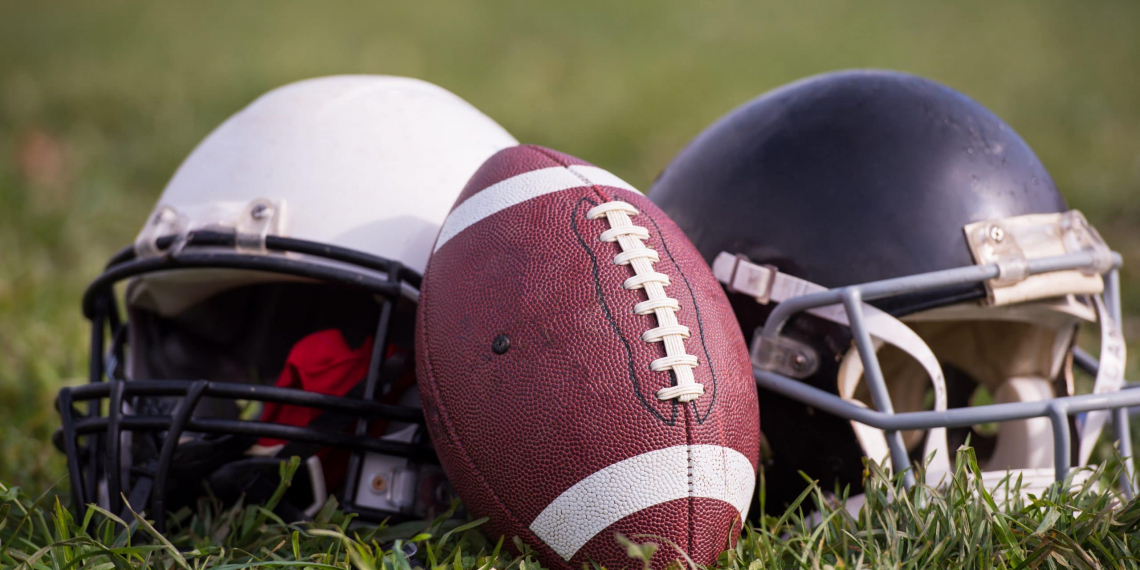American football helmets and ball lying on field