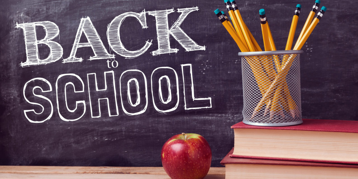 Back to school lettering with books, pencils and apple over chalkboard background