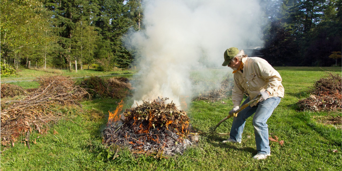 Man feeds an outdoor garden refuse burn