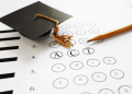 ACT college entrance test with pencil and  graduation cap