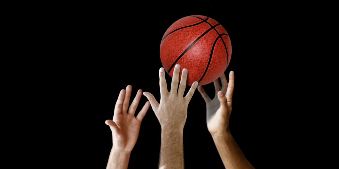 Players hand reaching for basketball in a competition