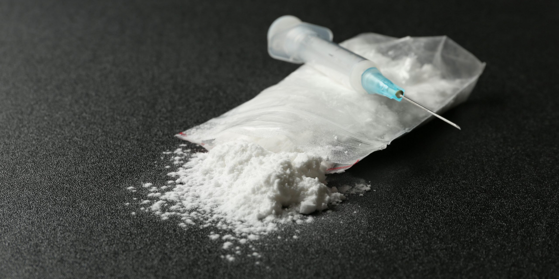 Cocaine in plastic bag and syringe on dark background