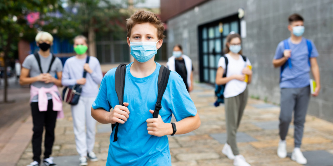 Portrait of teenager in protective mask with backpack going to school lessons on sunny autumn day. New lifestyle during coronavirus pandemic