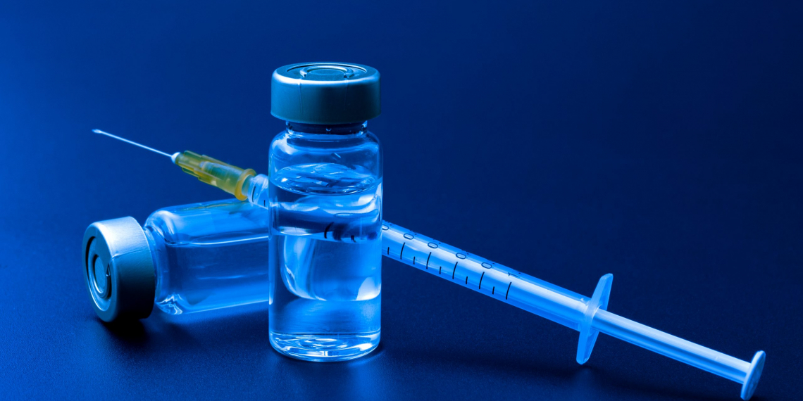 Vaccines, botulinum toxin and insulin ampules concept theme with glass vials with clear liquid next to a syringe and a hypodermic needle isolated on black background